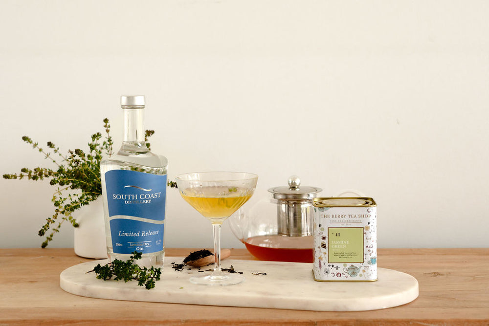 Image of South Coast Distillery gin with martini glass and The Berry Tea Shop Jasmine Green Tea tin and tea in the teapot