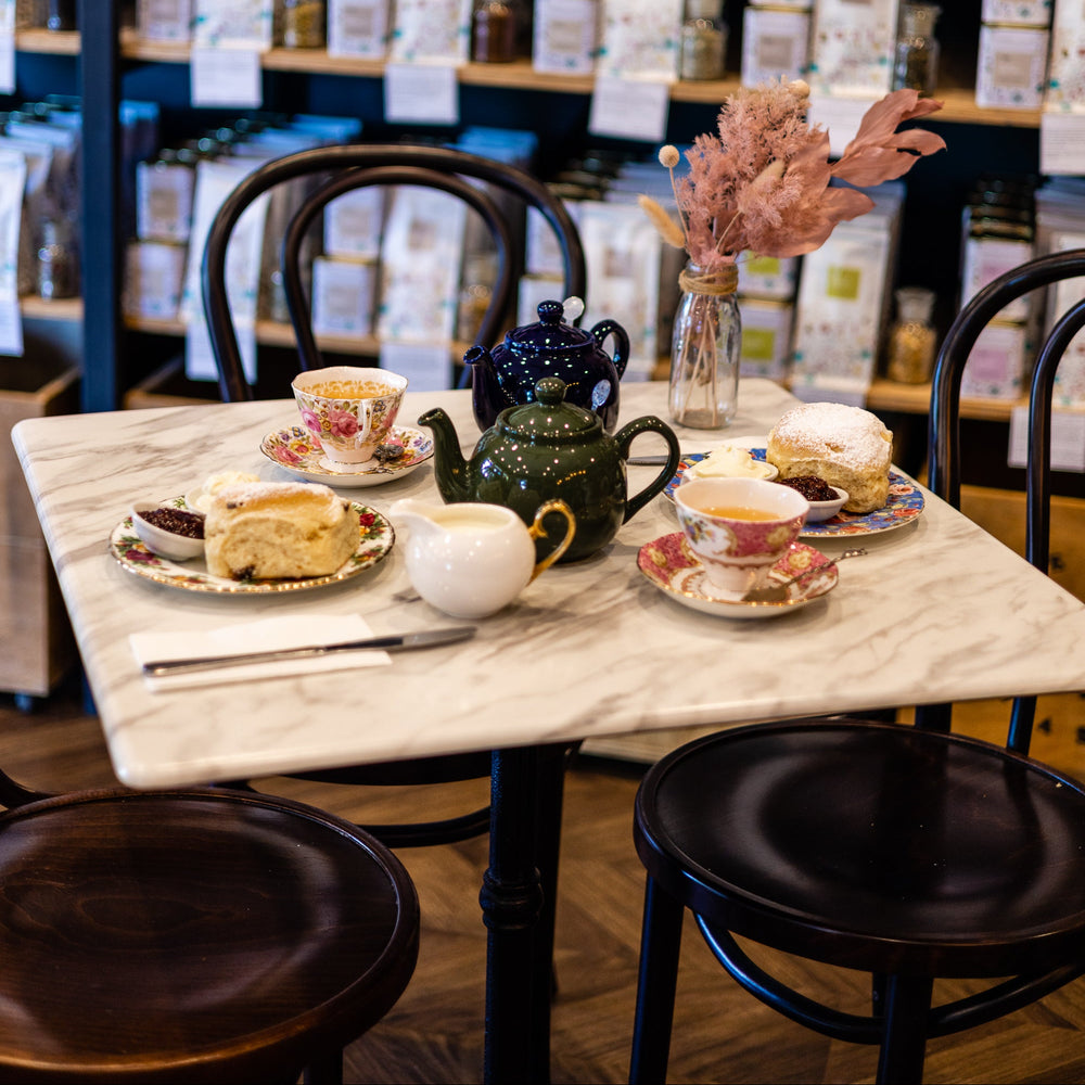 Tea set on a marble table with shelves displaying tea bags in the background